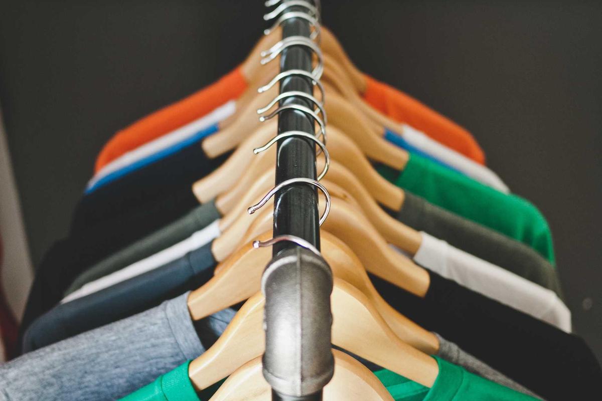 Des t-shirts de couleur alignés sur un portant de boutique.